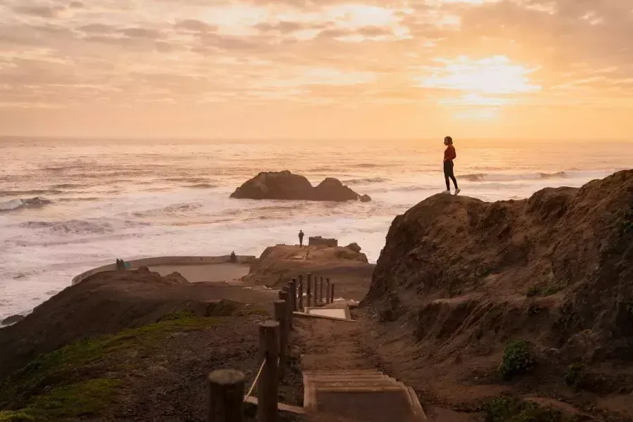 Two people stand on rocks overlooking the ocean at 海水浴场 in San Francisco.