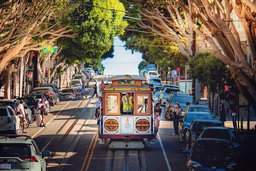 A 贝博体彩app cable car approaches on a tree-lined street.